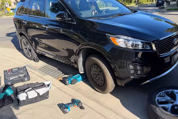Technician changing a passenger-car tire with an impact wrench